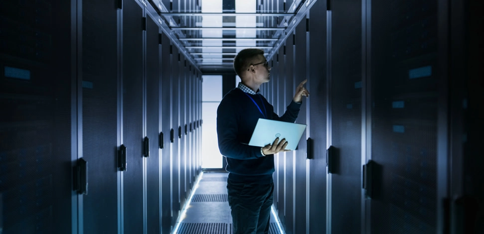 man-holding-laptop-looking-at-servers---The-Rising-Need-for-5G-Test-Lab-Power-Conservation-Solutions